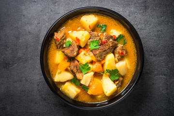 Goulash with meat and vegetables on black background. 