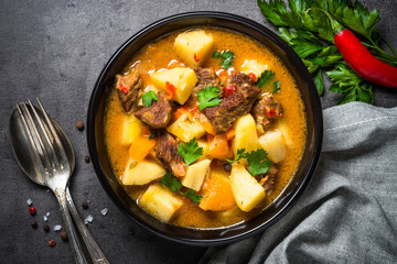 Goulash with meat and vegetables on black background. 
