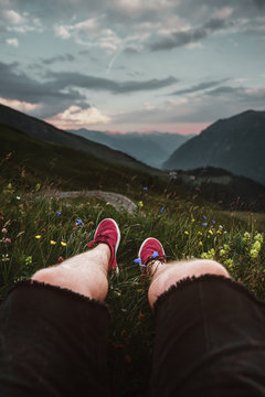 Mann sitzt auf eine Wiese bei Sonnenuntergang an der Grossglockner H&ouml;henstrasse und bilckt auf die Alpen