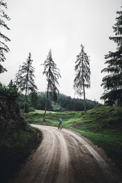 Junge Frau wandert entlang einer Bergstrasse in den chiemgauer Alpen mit Rucksack