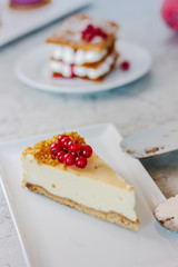 Cheesecake with red currant berries on white plate.