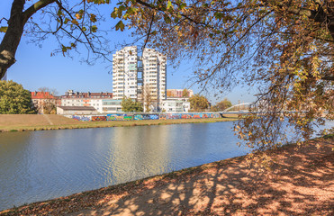 Opole, an autumn view of  walking areas on the Oder river and modern residential building on  other side of river - obrazy, fototapety, plakaty