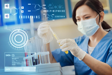 Working with samples. Concentrated serious lab worker carefully holding a test tube while dropping...
