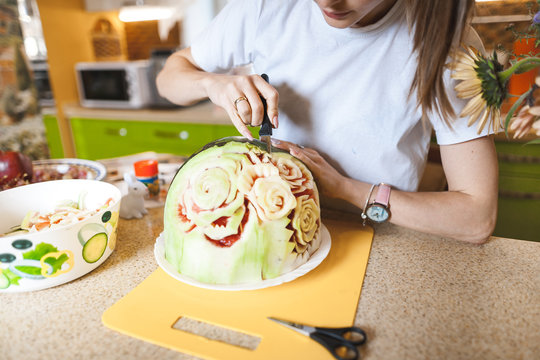 A young girl carving watermelon in her beautiful kitchen. Photo hobby
