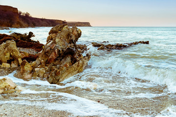 Sunset on the Black Sea, a large stone on the shore, waves, Cape Lucull, Crimea, Russia