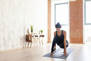 Woman practicing yoga positions in loft sport studio. Female fitness instructor in a yoga posture...