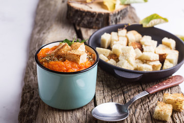 Autumn pumpkin soup served on wooden table in rural mugs