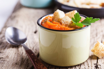 Autumn pumpkin soup served on wooden table in rural mugs