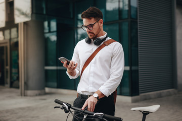 Businessman looking at his mobile phone standing outdoors