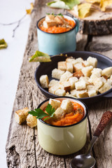 Autumn pumpkin soup served on wooden table in rural mugs