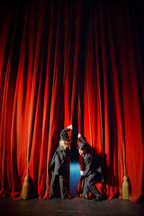 Actor and actress in tuxedos close the theater curtain