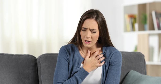 Front view of a woman suffering an anxiety attack sitting on a couch at home