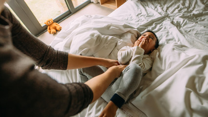 Mother tickling her boy on the bed - obrazy, fototapety, plakaty