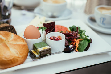 Frühstückstisch in Restaurant, Brötchen, Ei, Butter und Salat