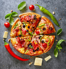 Italian pizza with fresh ingredients viewed from above on a dark grey background. Top view