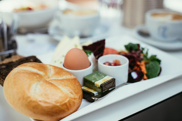 Frühstückstisch in Restaurant, Brötchen, Ei, Butter und Salat
