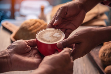 Barista's hands are delivering coffee to customers.