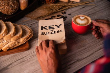 Hand holding a cup of coffee and reading a book key of success - concept lifestyle