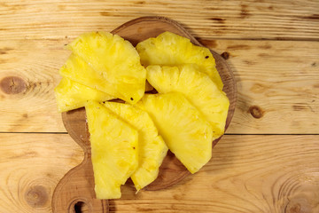 Pieces of pineapple on a cutting board on wooden table. Top view