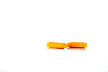 Two orange pills on a neutral background.