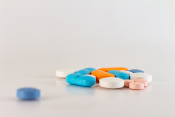 Numerous colored pills on a neutral background.
