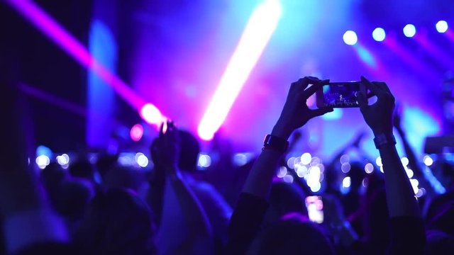 People taking photos or recording video with smartphones at live concert. Slow motion