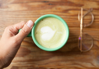 Overhead close up image of a hot drink in a mug with glasses on the background