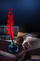 Red quill pen and a rolled papyrus sheet on a wooden table with old books