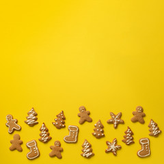 Homemade christmas cookies on yellow background with copy space. Square crop. Pattern of gingerbread men, snowflake, star, fir-tree, boot shapes. New year concept