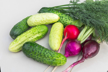 Cucumbers, radishes, dill on the white surface of the table