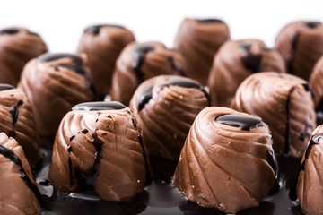 pieces of bonbons covered with melted chocolate on white background
