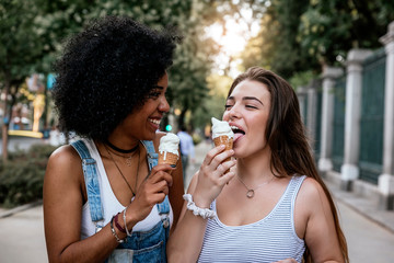 Beautiful women eating one ice cream in the street.