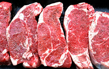 Seasoned steaks on black background.