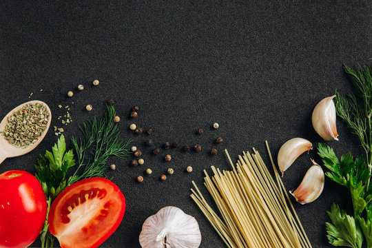 Spaghetti and pasta ingredients on a dark background, top view