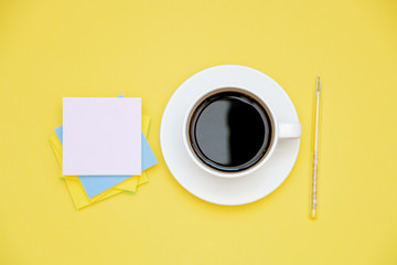pen and stickers coffee Cup on yellow background with copy space top view