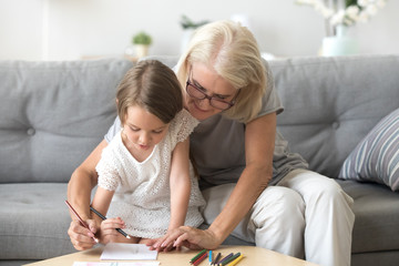 Grandmother and granddaughter paint picture with colorful pencils together, granny and grandchild...
