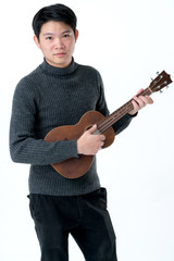 friendly asian man enjoy play and sing with ukulele grey tshirt white background