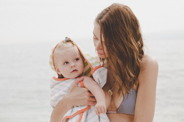 Fototapeta na wymiar Mother holding adorable baby girl, on the beach, family summer vacation concept