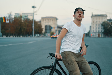 Fototapeta premium Outdoor portrait of a modern young man in the street, sitting on bike