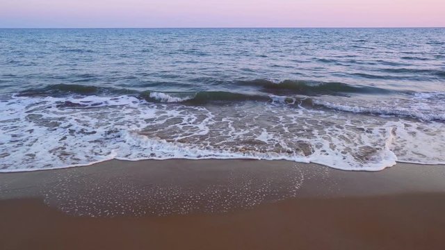 Waves breaking on shore at blue hour on a sandy beach in Costa dorada, Spain. Mediterranean sea waves in Altafulla, Spain.