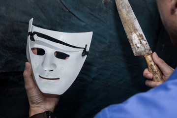The man holding white mask threatens , killer concept, horror theme , Halloween concepts
