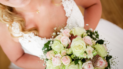 Naklejka premium Braut im Hochzeitskleid hält Brautstrauß mit Rosen