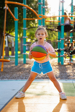 A girl playing with a basketball at a park. 