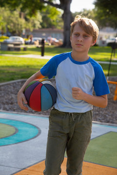 A boy playing with a basketball at the park. 