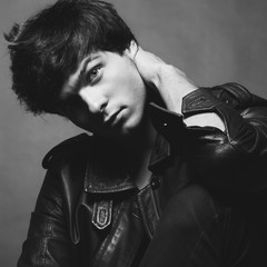 Portrait of Handsome Young Man. A Men in a Leather Jacket posing on a Gray Background. Black And White Photo