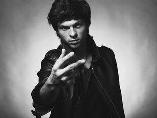 Portrait of Handsome Young Man. A Men in a Leather Jacket posing on a Gray Background. Black And White Photo
