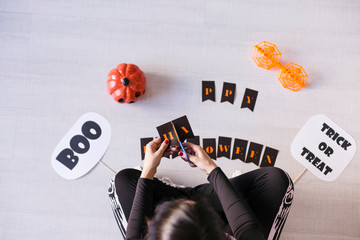 top view of a young woman makes Halloween garland.Creative DIY . Home decor project party.Halloween crafts inspiration.