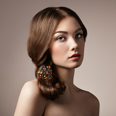 Portrait of young beautiful girl. Fashion photo. Girl with a vintage brooch in her hair. Beautiful Model Woman with Wavy Hairstyle