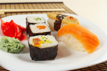 Sushi with omelet with unagi and with salmon and rolls on a bamboo mat close up.