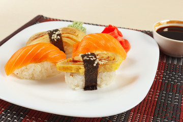 Sushi set and soy sauce on a black and red bamboo mat close up.